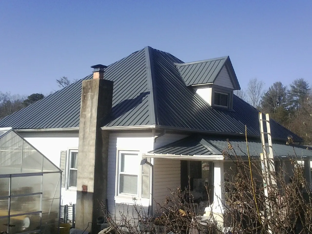 Dark blue standing seam metal roof on a white farmhouse with dormer — Slate & Tile Roof Repair by Roofing Brothers in Barnegat Light