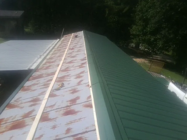 Old rusted panels beside newly installed green metal roofing — Wind Damage Roof Repair by Roofing Brothers in Barnegat Light