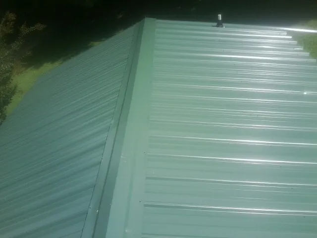New green metal panels meeting at the ridge of a roof — Flat Roof Repair work by our crew in Barnegat Light