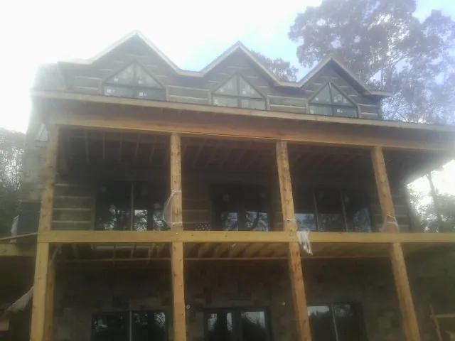 Dormers and porch framing on a large log home under construction — Roof Coating work by our crew in Barnegat Light