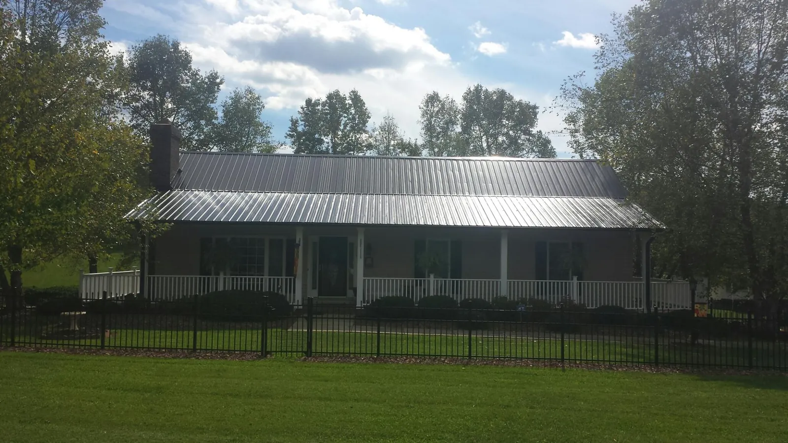 Gray metal roof on a brick ranch with a full width front porch — Gutter Guard Installation work by our crew in Barnegat Light