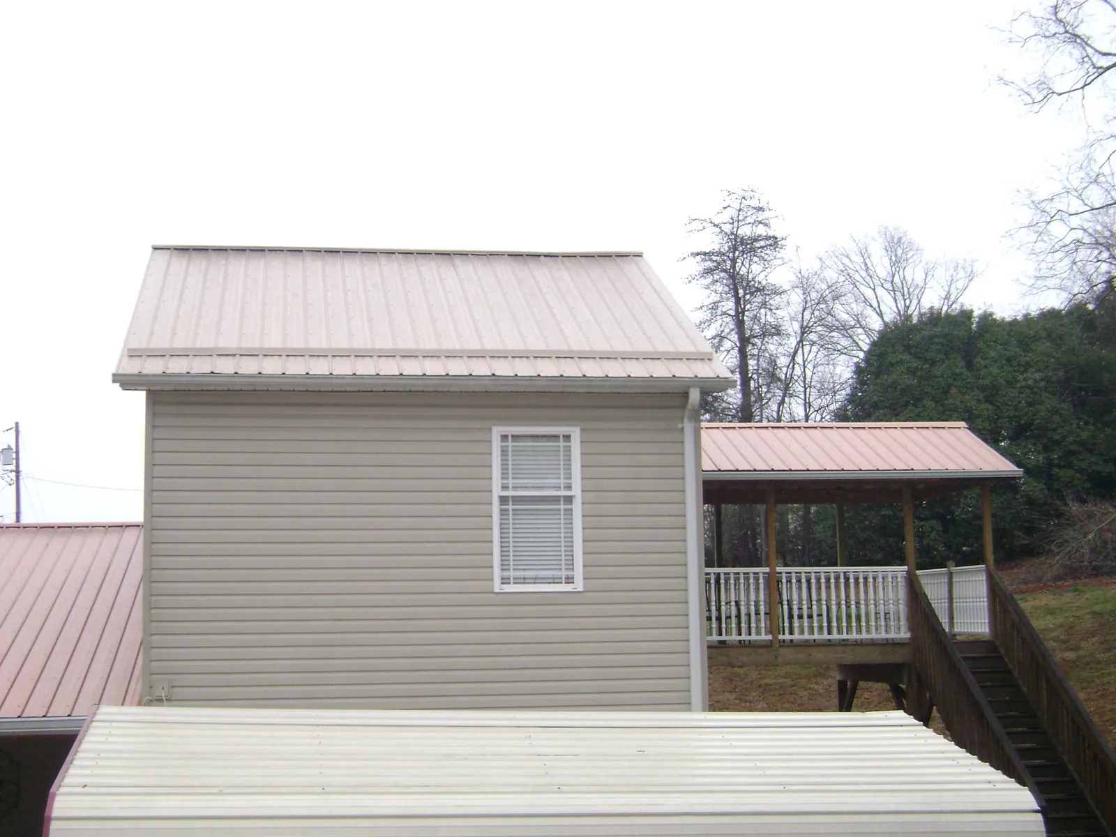 Tan metal roofs on a two story addition and attached porch, from a Roof Replacement job in Barnegat Light