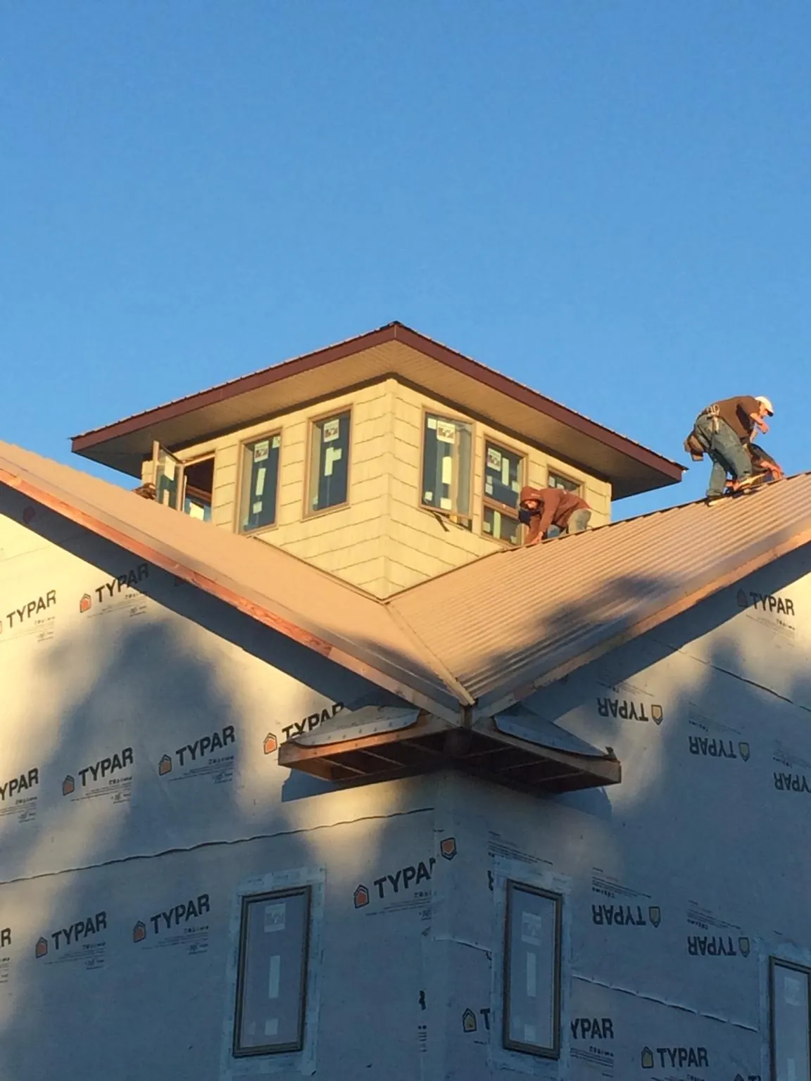 Roofers working around a rooftop cupola on a new metal roof at sunset — Roof Waterproofing in Barnegat Light by Roofing Brothers